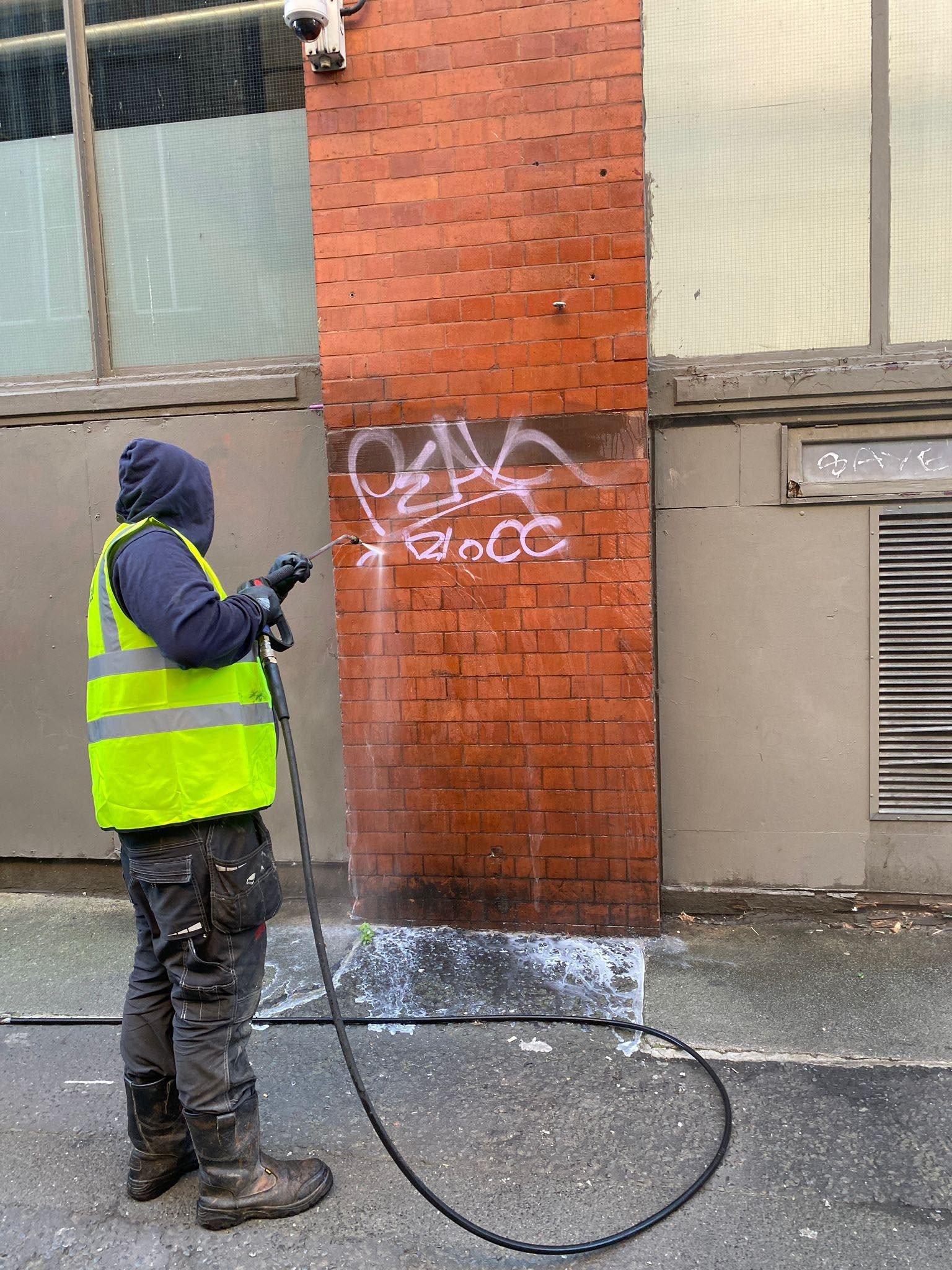 Metal shutter being cleaned of graffiti